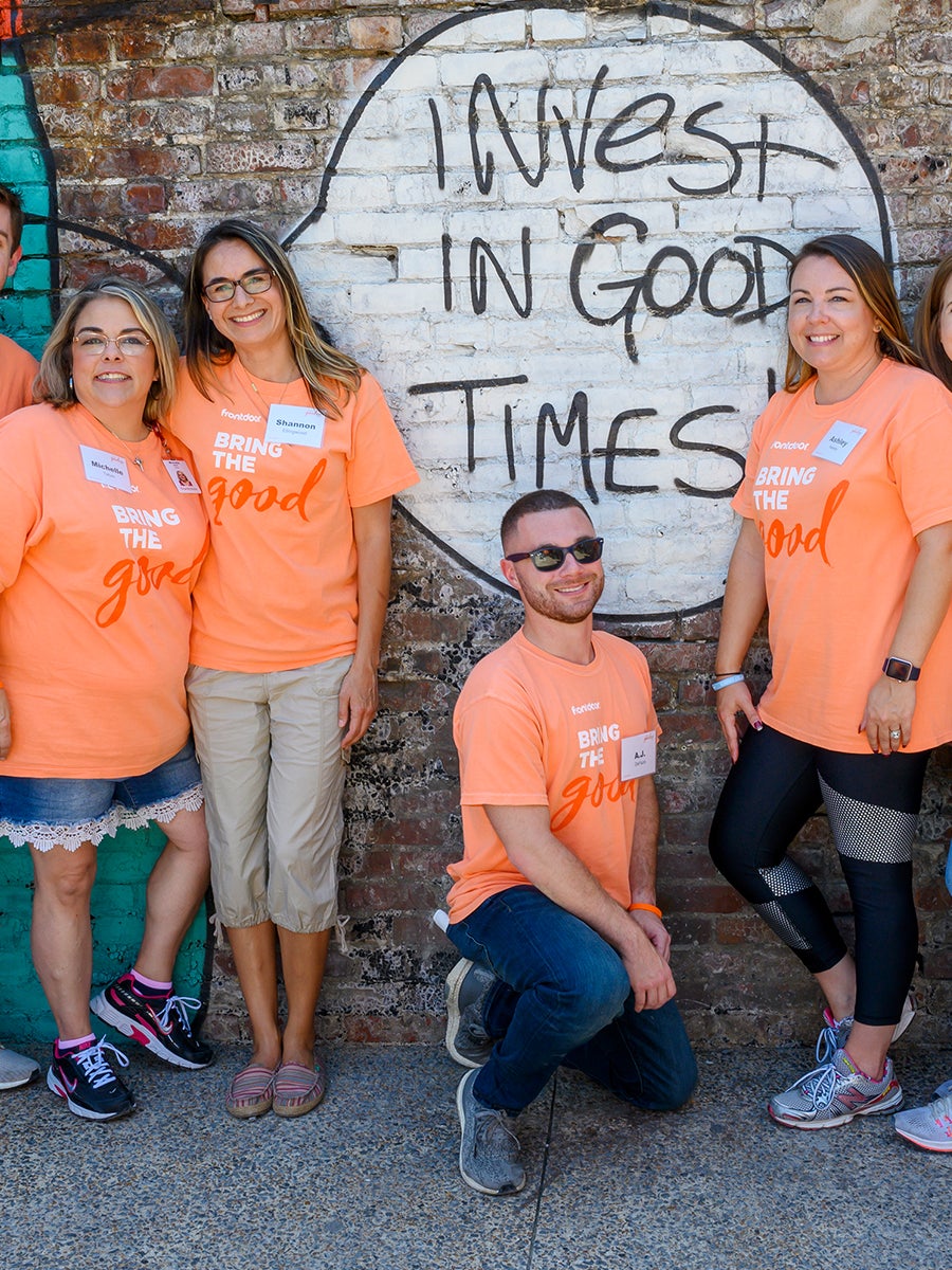 Members of the Frontdoor staff posing in front of a mural on Good Day..